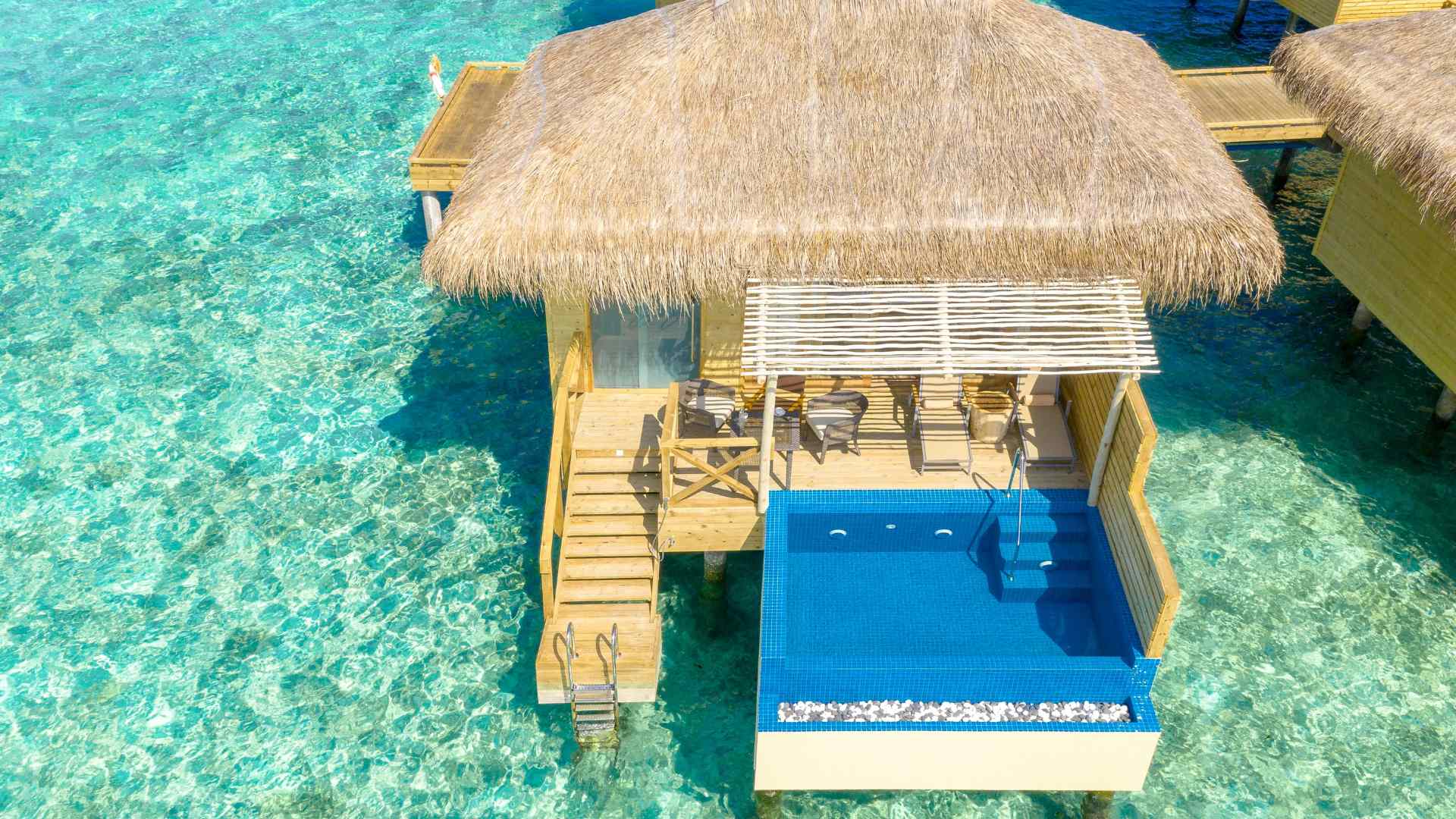 Overwater resort buildings above calm blue water