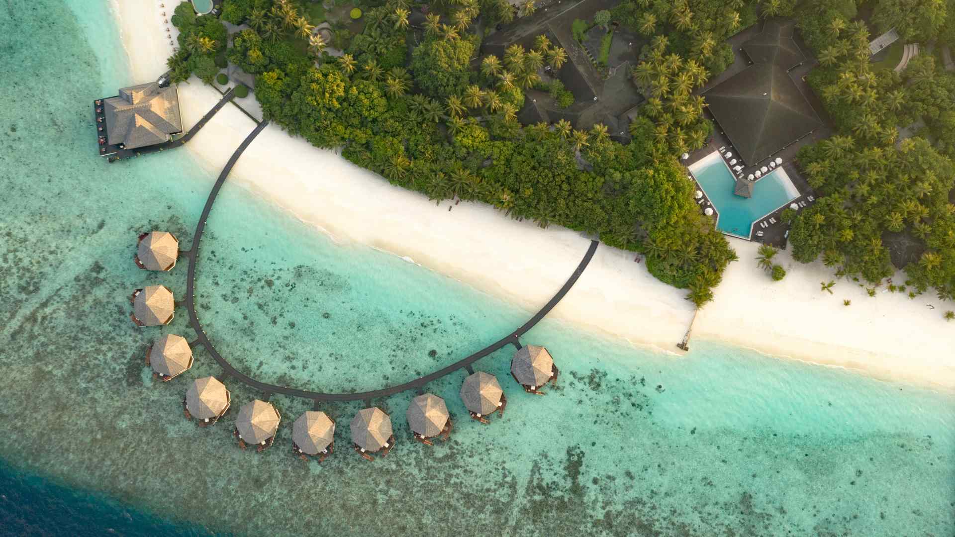 Aerial view of a tropical island resort and overwater bungalows