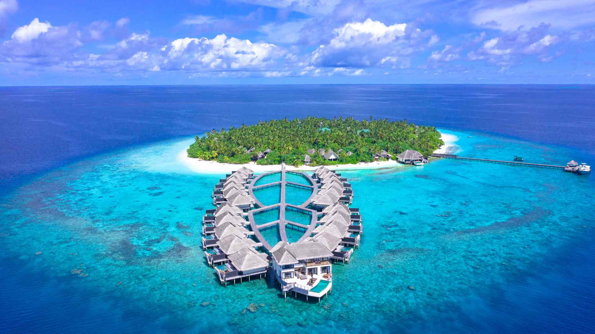 Aerial view of a tropical island with an overwater villa jetty