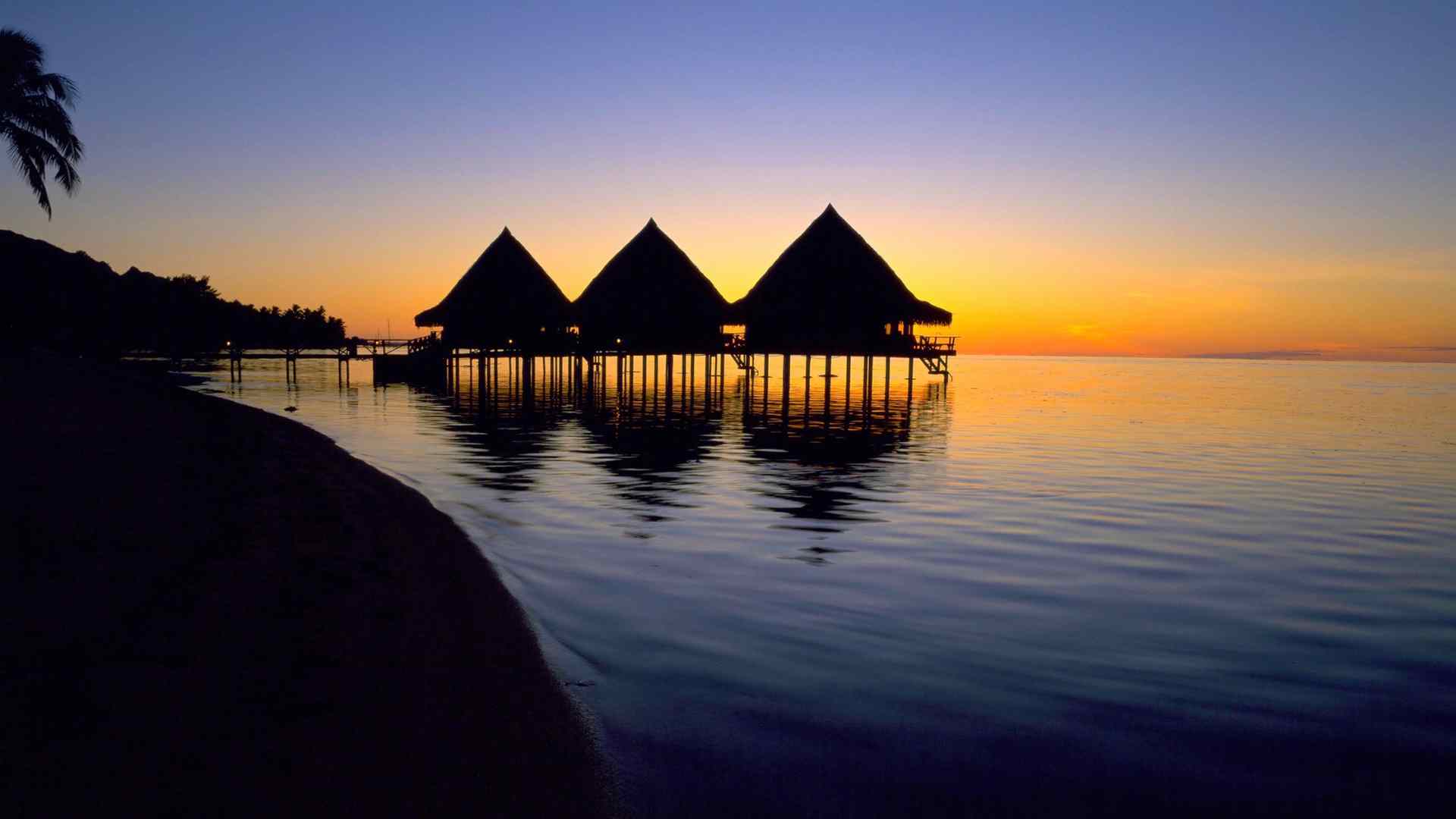 Overwater bungalows silhouetted at sunset in French Polynesia