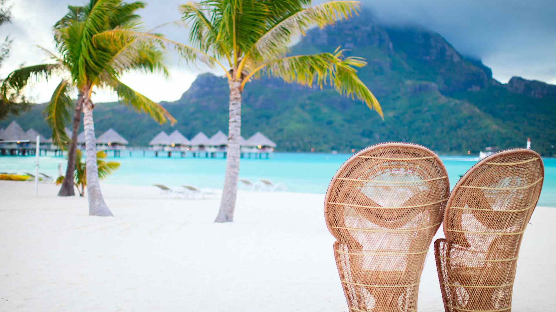 Overwater bungalows with a volcanic island backdrop in French Polynesia