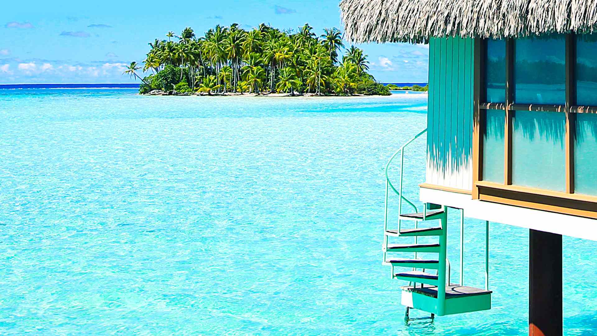 Overwater bungalow beside a bright French Polynesia lagoon and palm-covered islet