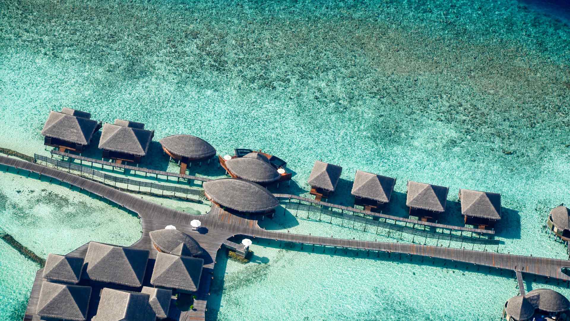 Aerial view of tropical overwater buildings and a long wooden boardwalk