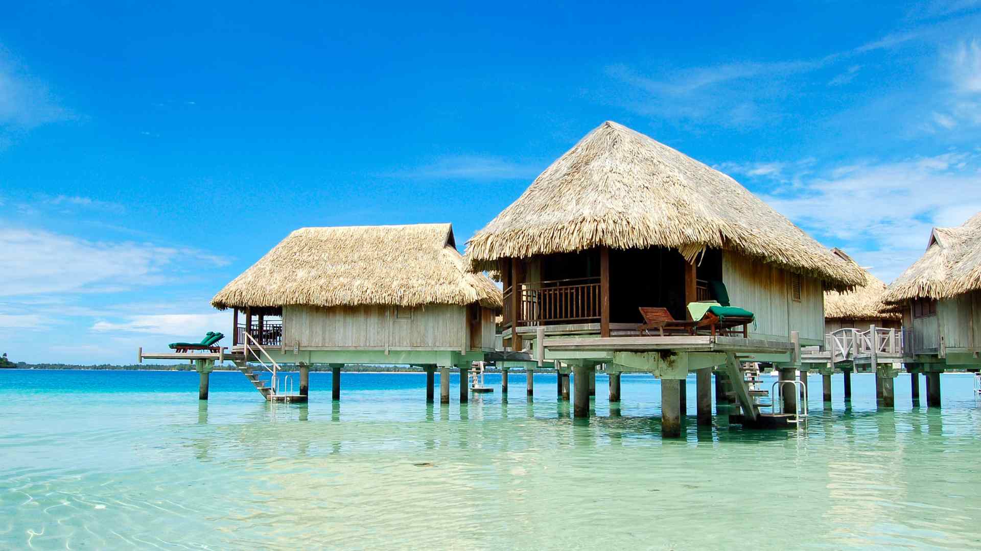 Thatched overwater bungalow with a private deck in tropical water