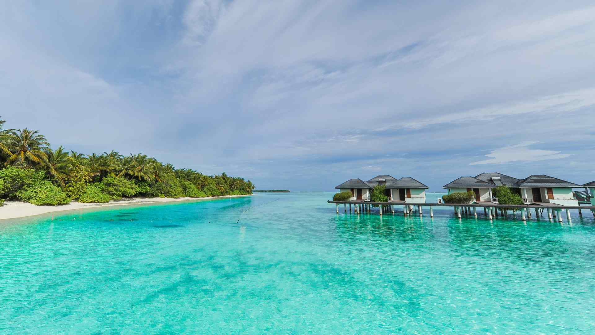 Illustrative row of overwater villas beside a tropical island, not Bahamas overnight accommodation