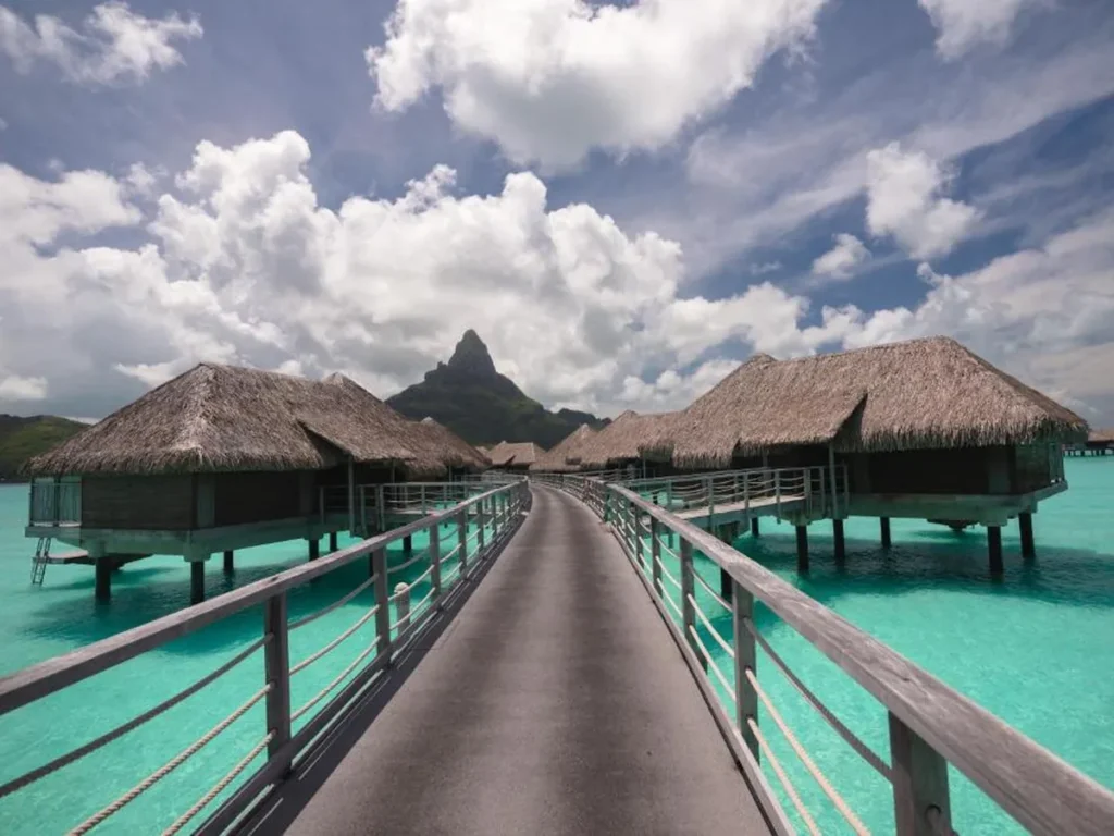 Long boardwalk to thatched Bora Bora overwater villas below Mount Otemanu