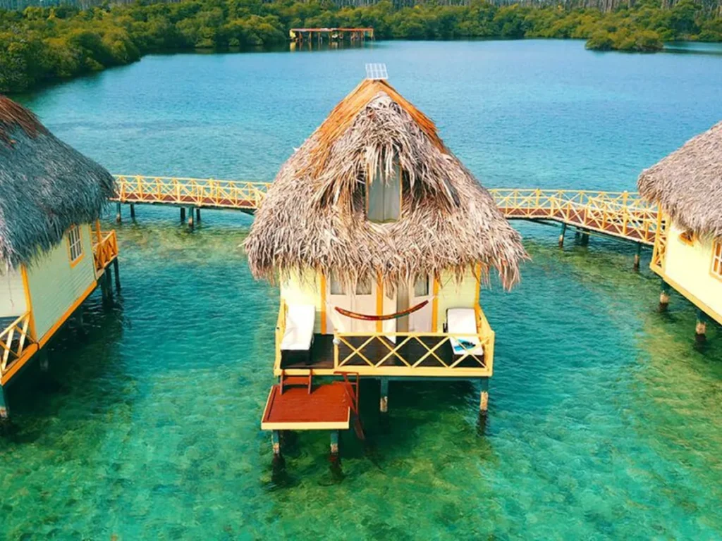 Thatched Punta Caracol overwater bungalow above clear Caribbean water